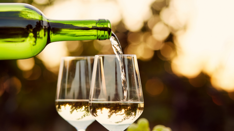 vins blancs liquoreux : bouteille de vin blanc liquoreux du Sauternais avec un paysage de vignoble en arrière-plan