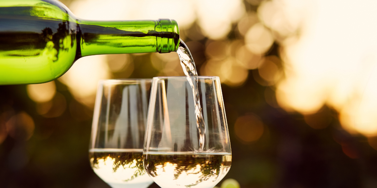 vins blancs liquoreux : bouteille de vin blanc liquoreux du Sauternais avec un paysage de vignoble en arrière-plan